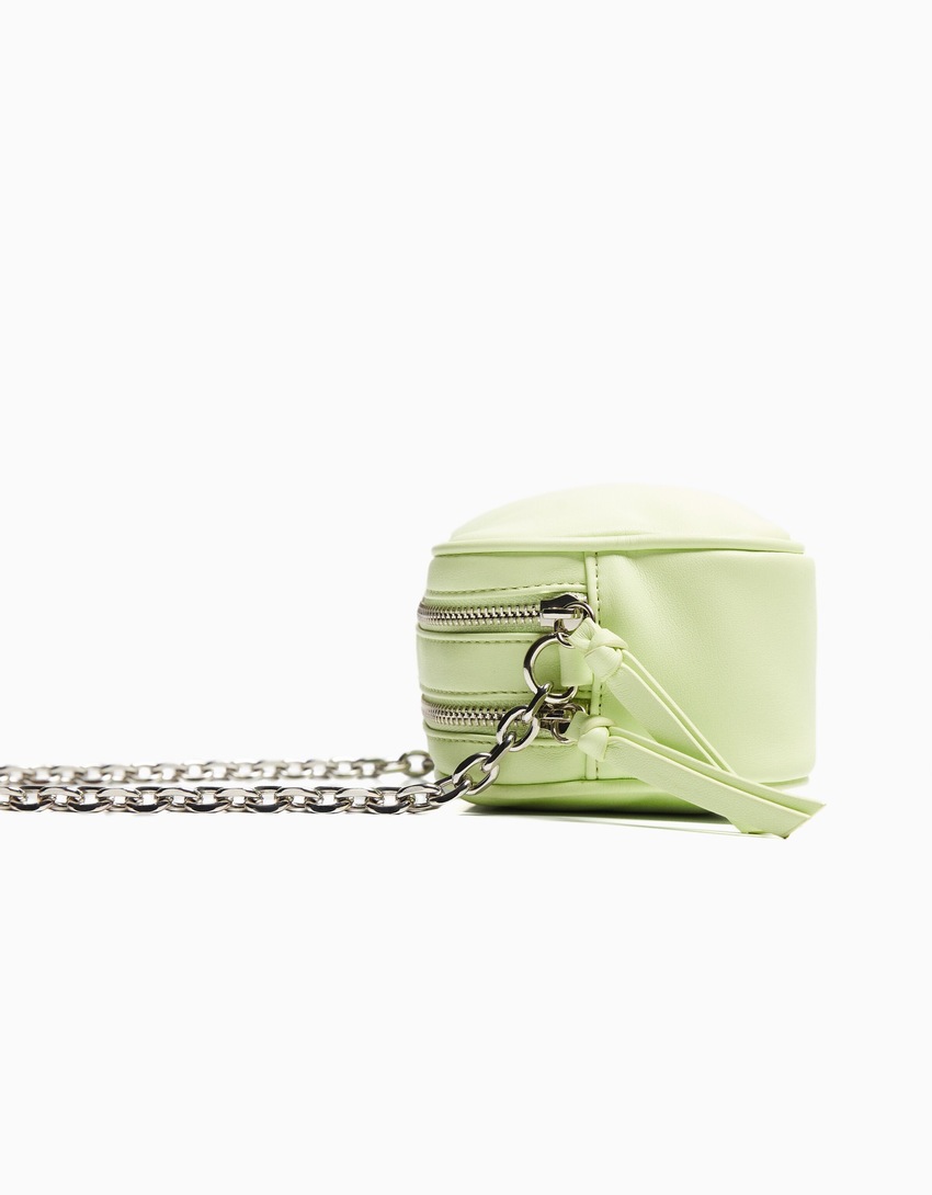 Bolsa transversal com fecho duplo de zíper e corrente.