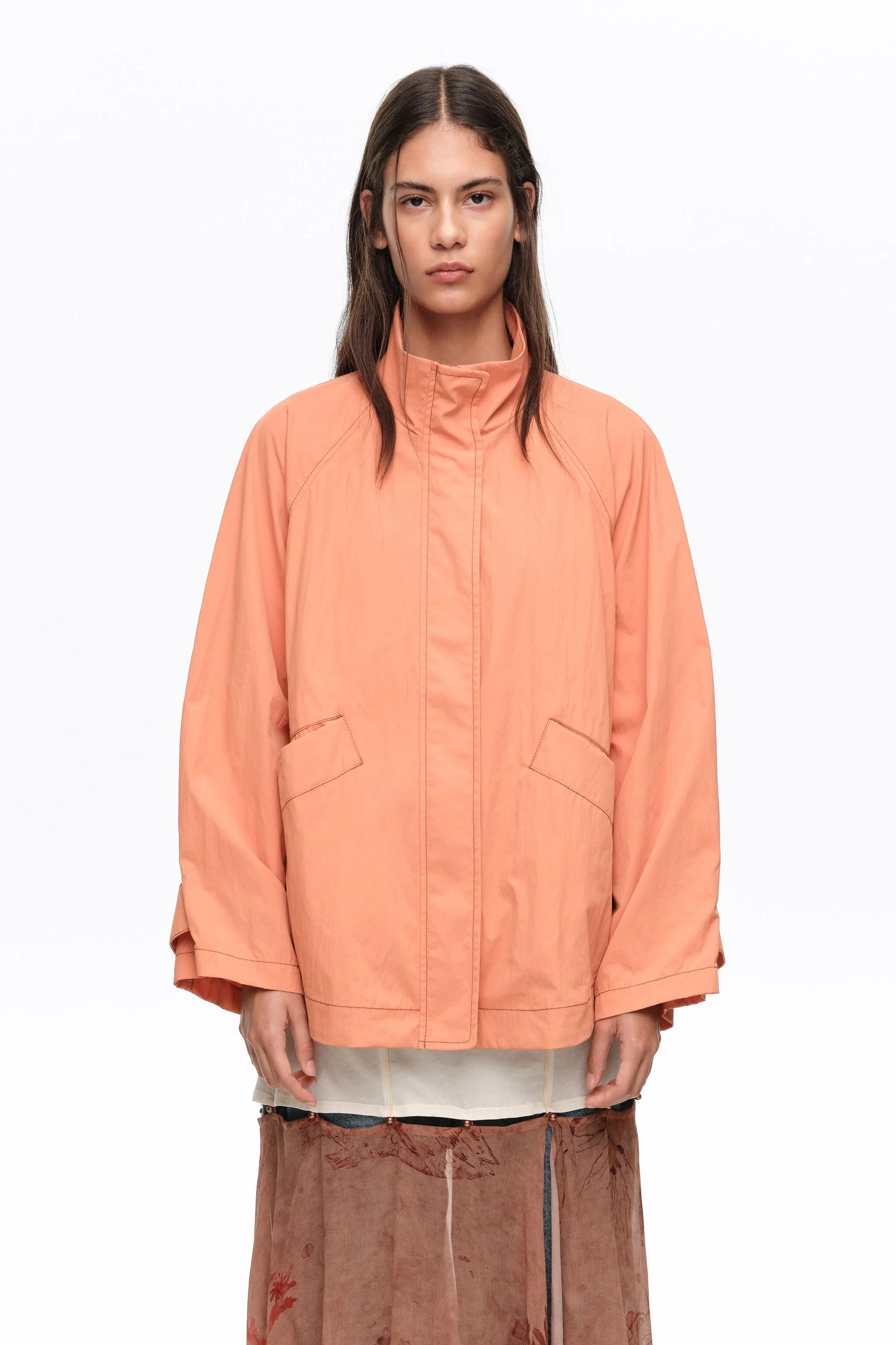 Trench coat curto, laranja, fluido, com gola alta.