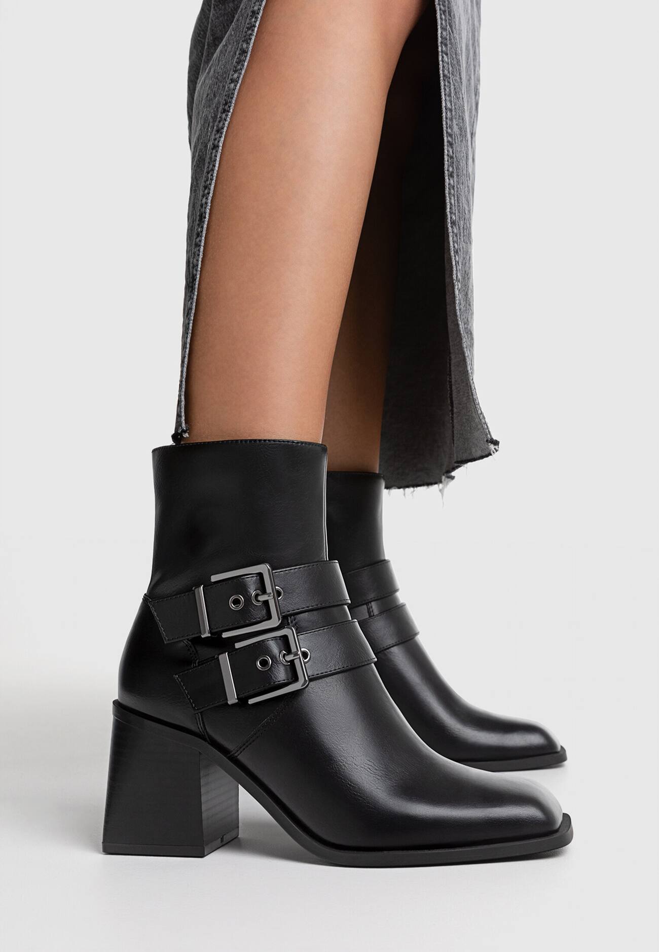 Botas pretas de cano curto com salto alto e fivelas.