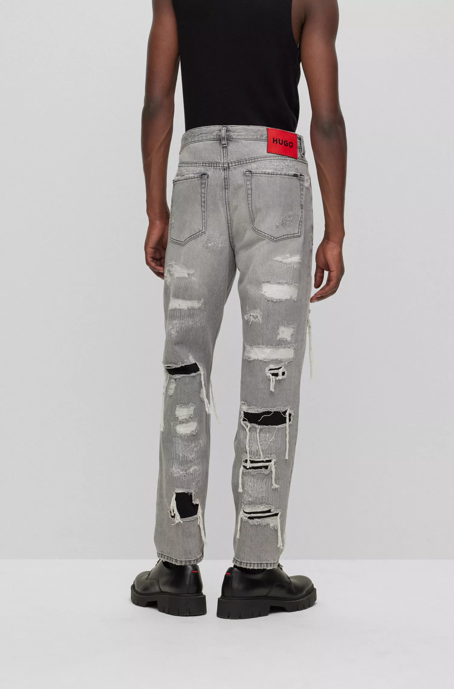 Calça jeans HUGO vermelha, corte afunilado, em denim cinza-prateado com efeito desgastado.