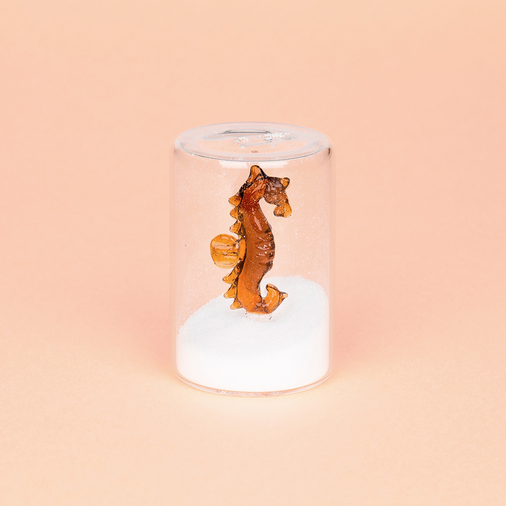 Colher de sal Balvi em formato de cavalo-marinho, cor âmbar, feita de borosilicato.