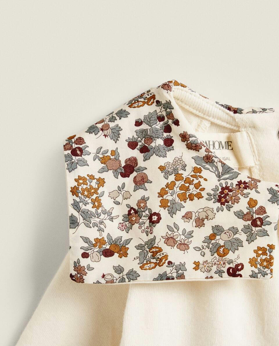 Macacão infantil em tecido com estampa floral e detalhe de gola.