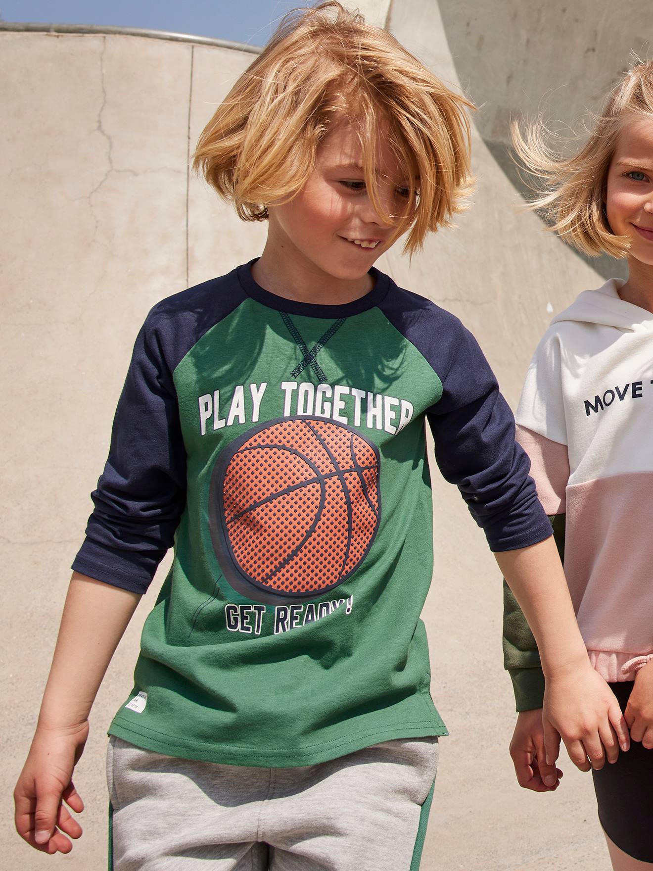 Camiseta esportiva infantil com estampa de bola em relevo e mangas raglan, verde médio liso com detalhes.