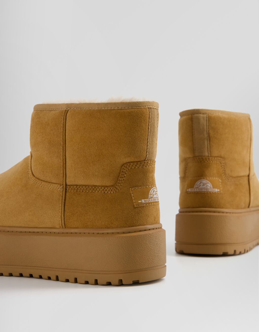 Botas de cano curto com plataforma e forro de pele sintética.