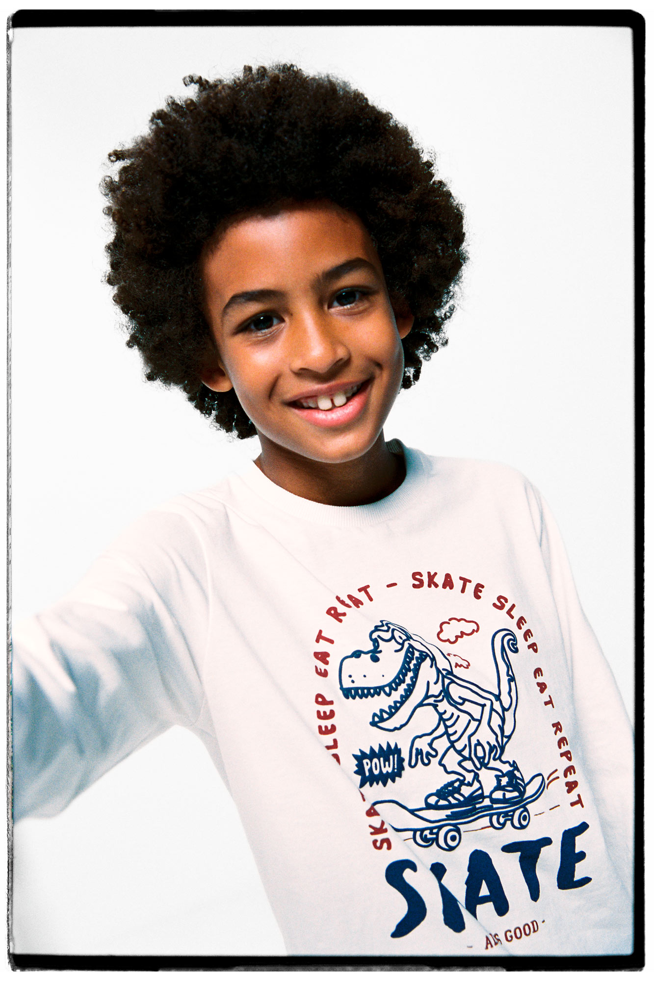 Camiseta infantil com estampa de dinossauro e skatista.