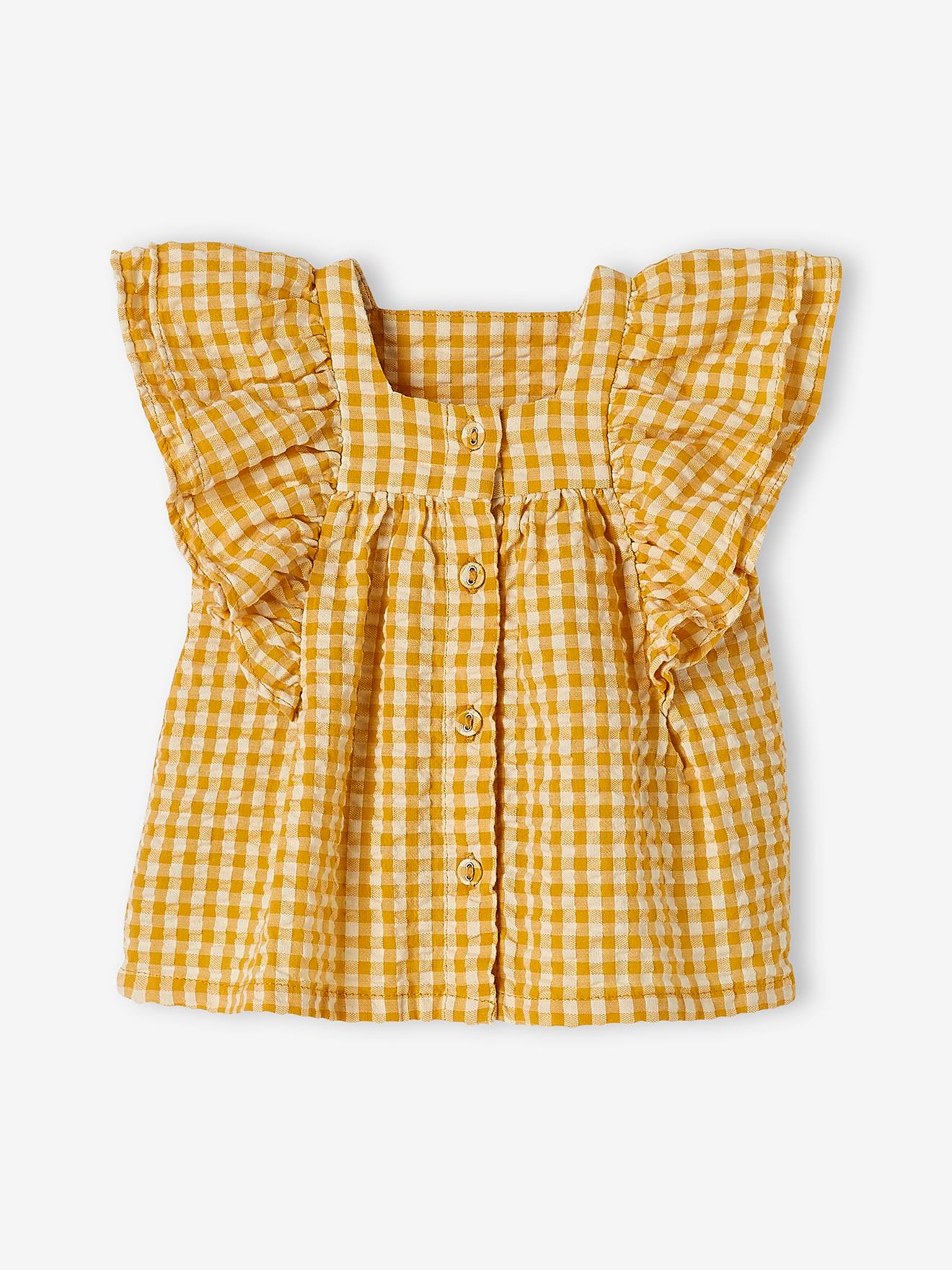Conjunto infantil tamanho médio com blusa xadrez amarela e calça jeans de pernas largas.