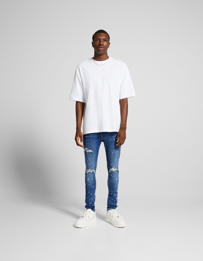 Calça jeans super skinny rasgada com respingos de tinta