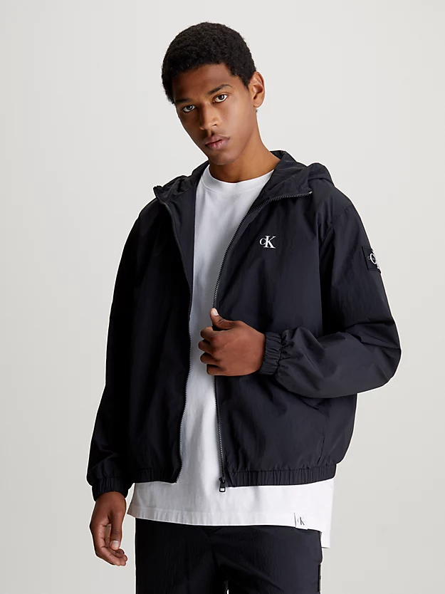 Jaqueta corta-vento de nylon com modelagem folgada e capuz.