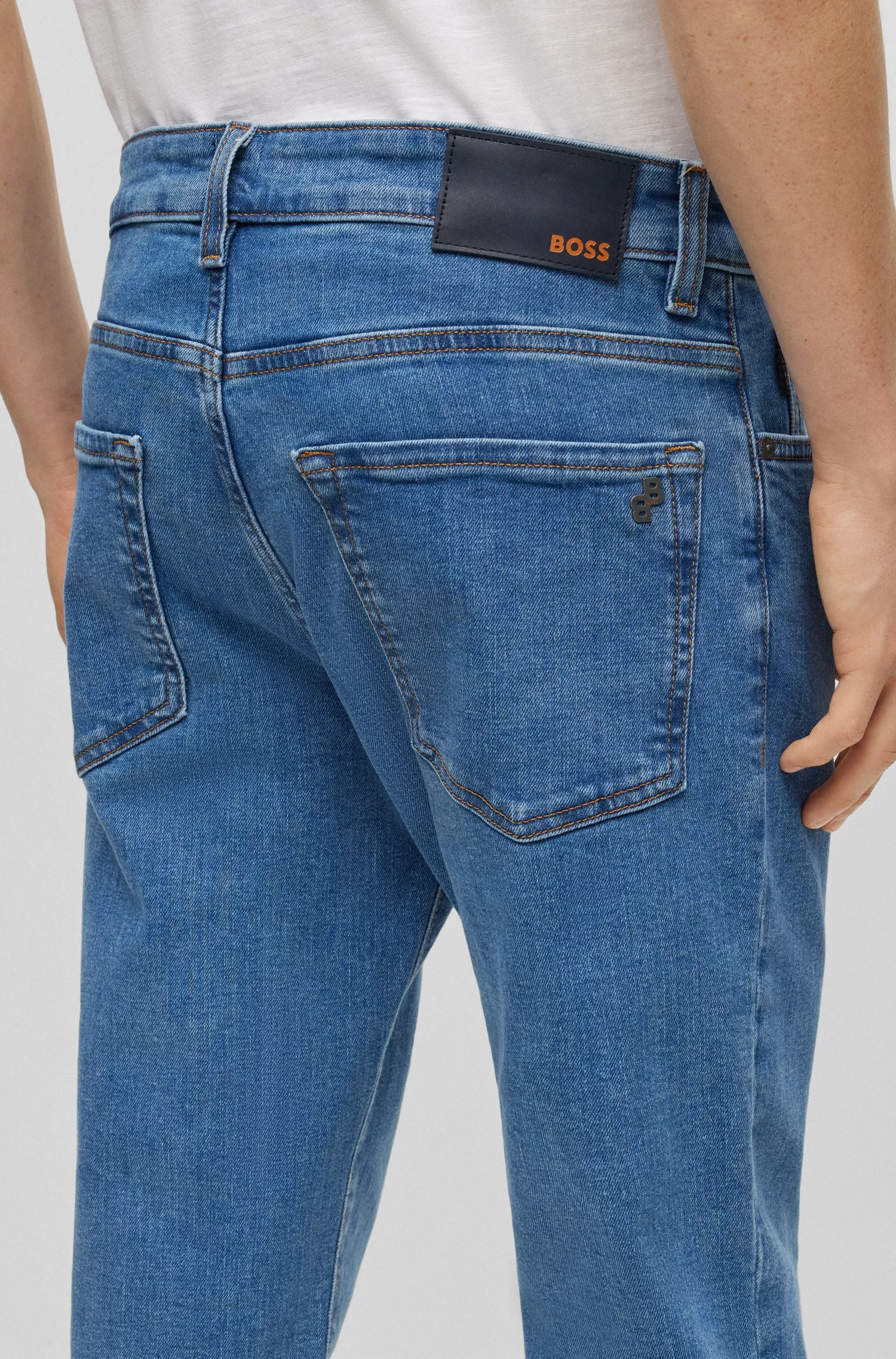 Calça jeans BOSS laranja, corte regular, em denim azul com elasticidade confortável.