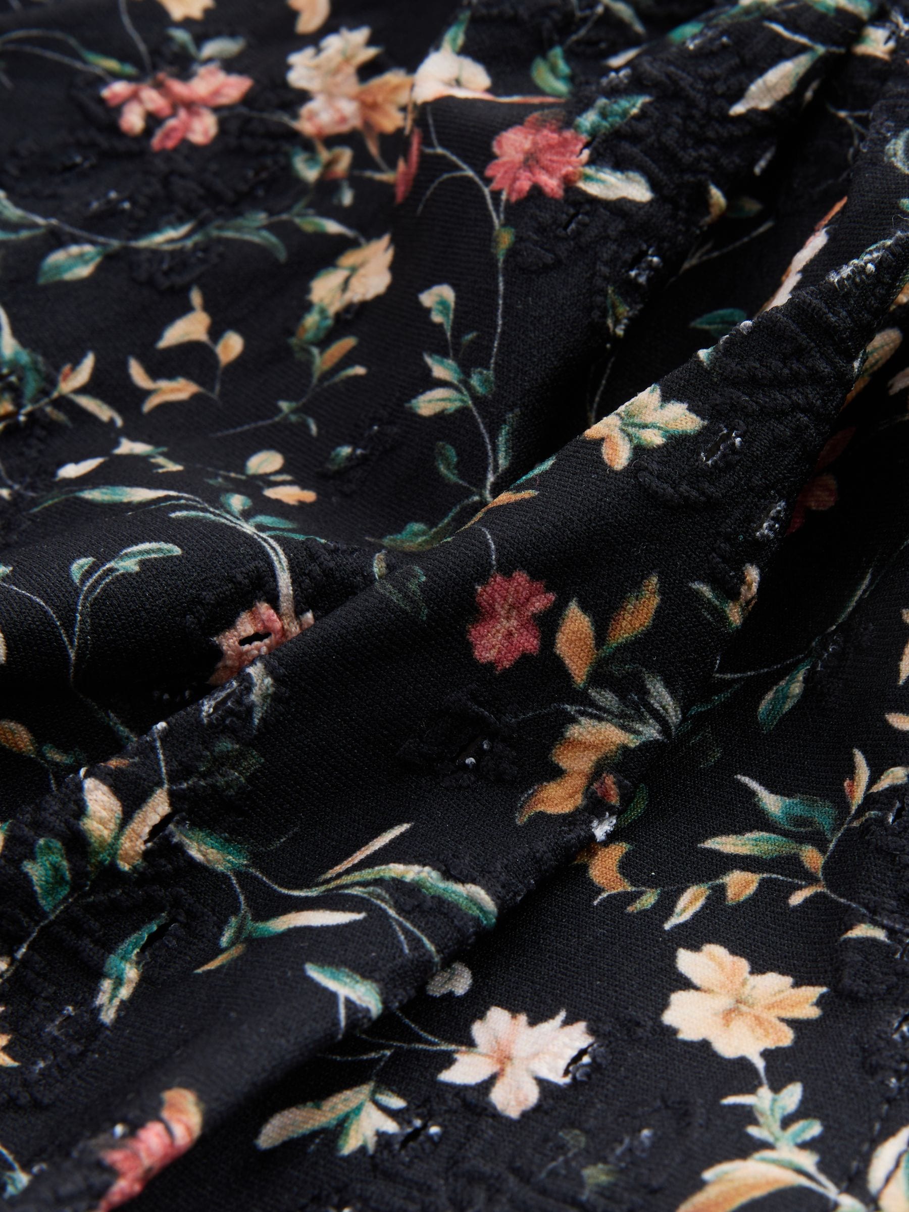 Zwart met broderie en fijne print - Badpak met vormgevende zijrimpeling en buikcorrectie