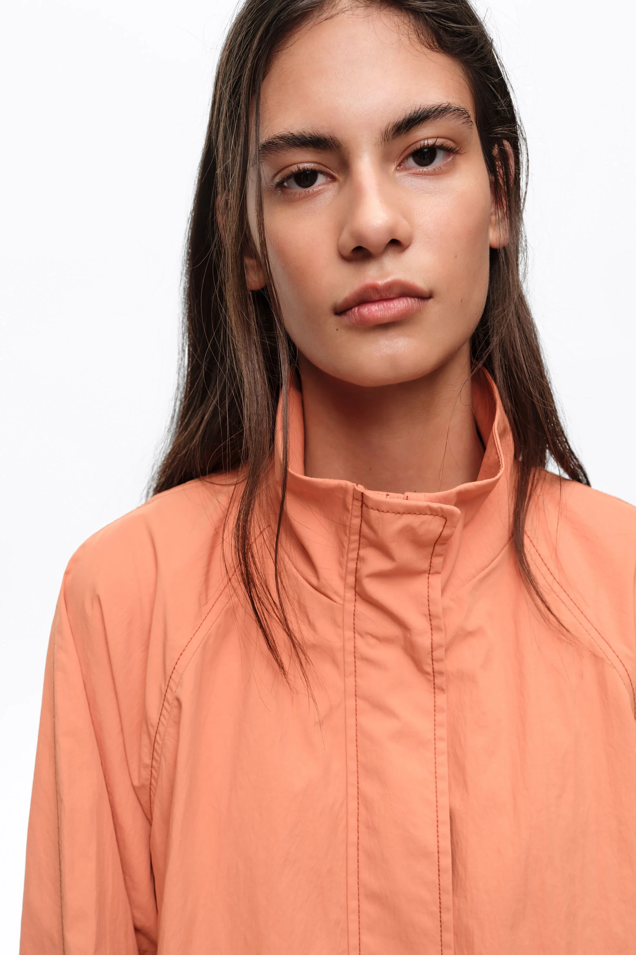 Trench coat curto, laranja, fluido, com gola alta.