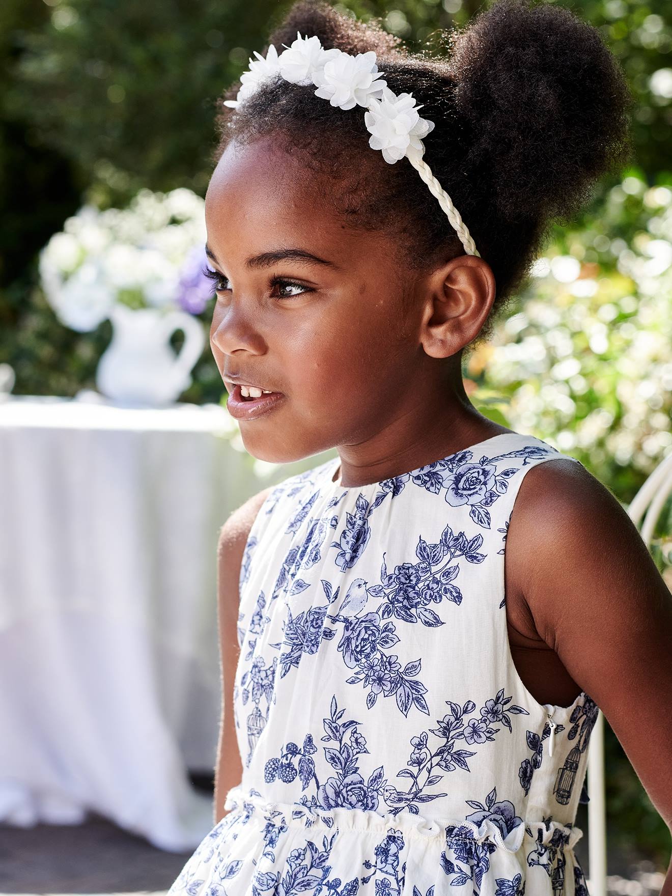 Vestido de festa infantil com flores e laço nas costas, na cor branco-creme.