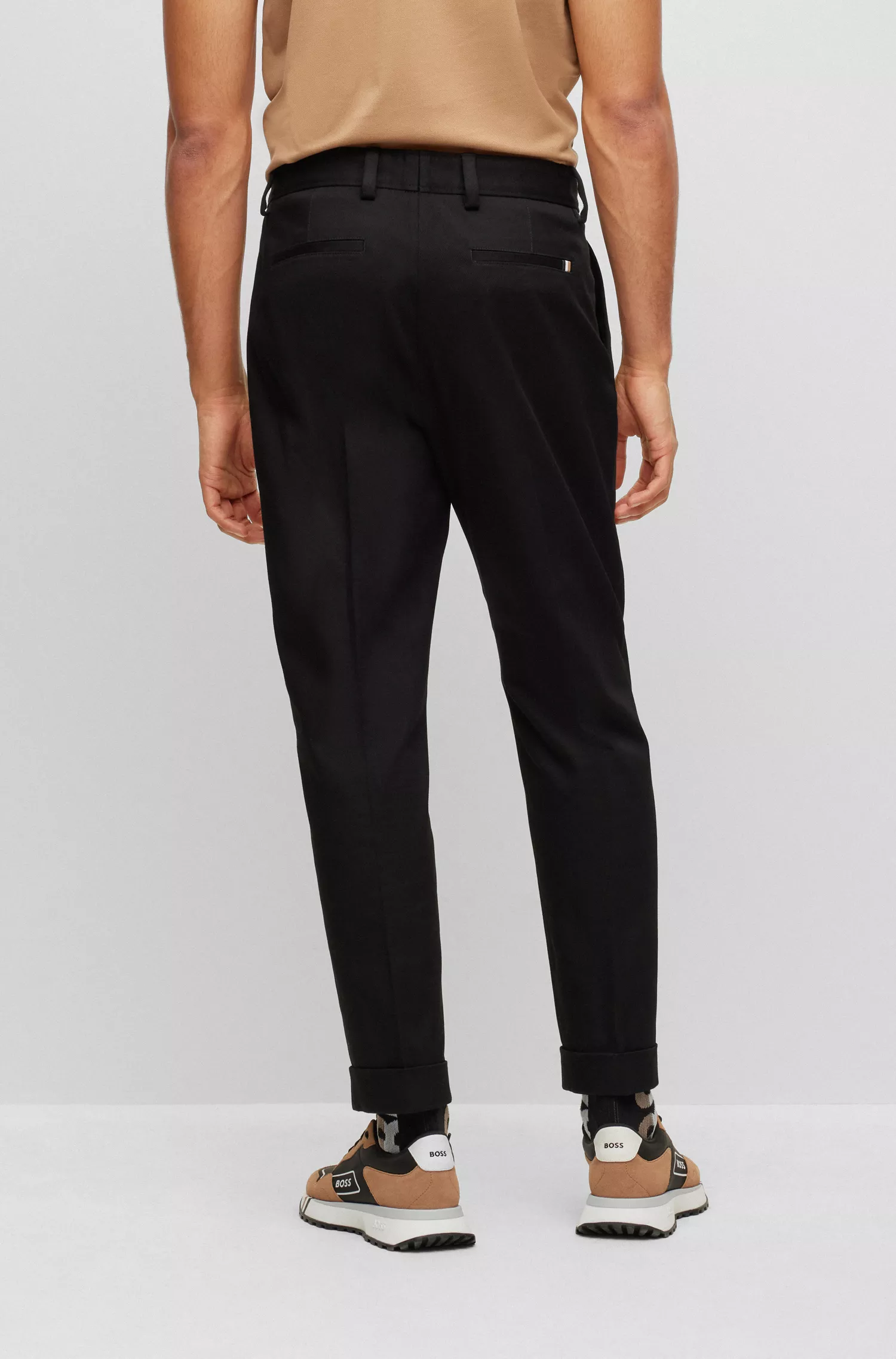 Calça BOSS preta de corte relaxado em algodão elástico com prega frontal.
