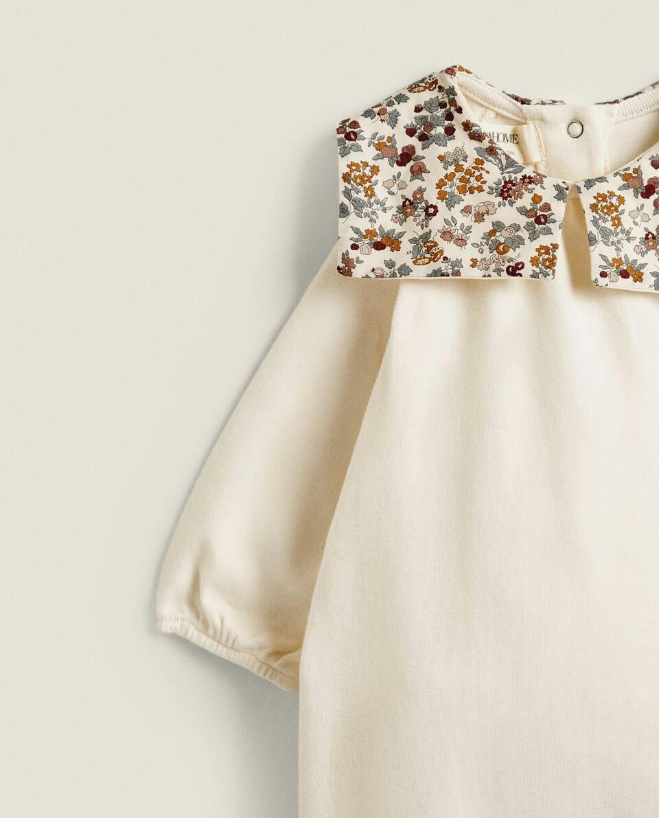 Macacão infantil em tecido com estampa floral e detalhe de gola.