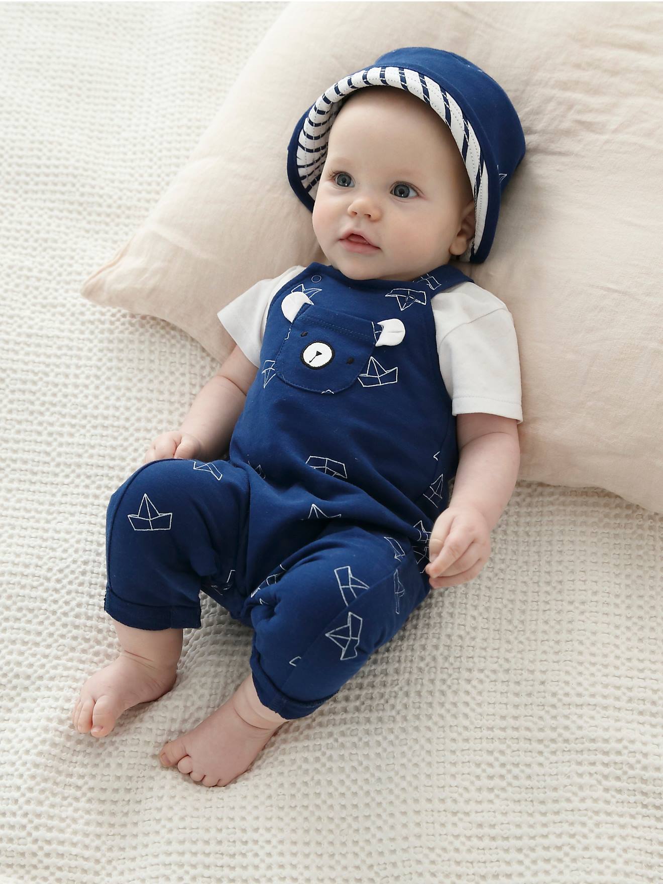 Conjunto para recém-nascido: gorro chanel, body e jardineira azul-escura estampada.