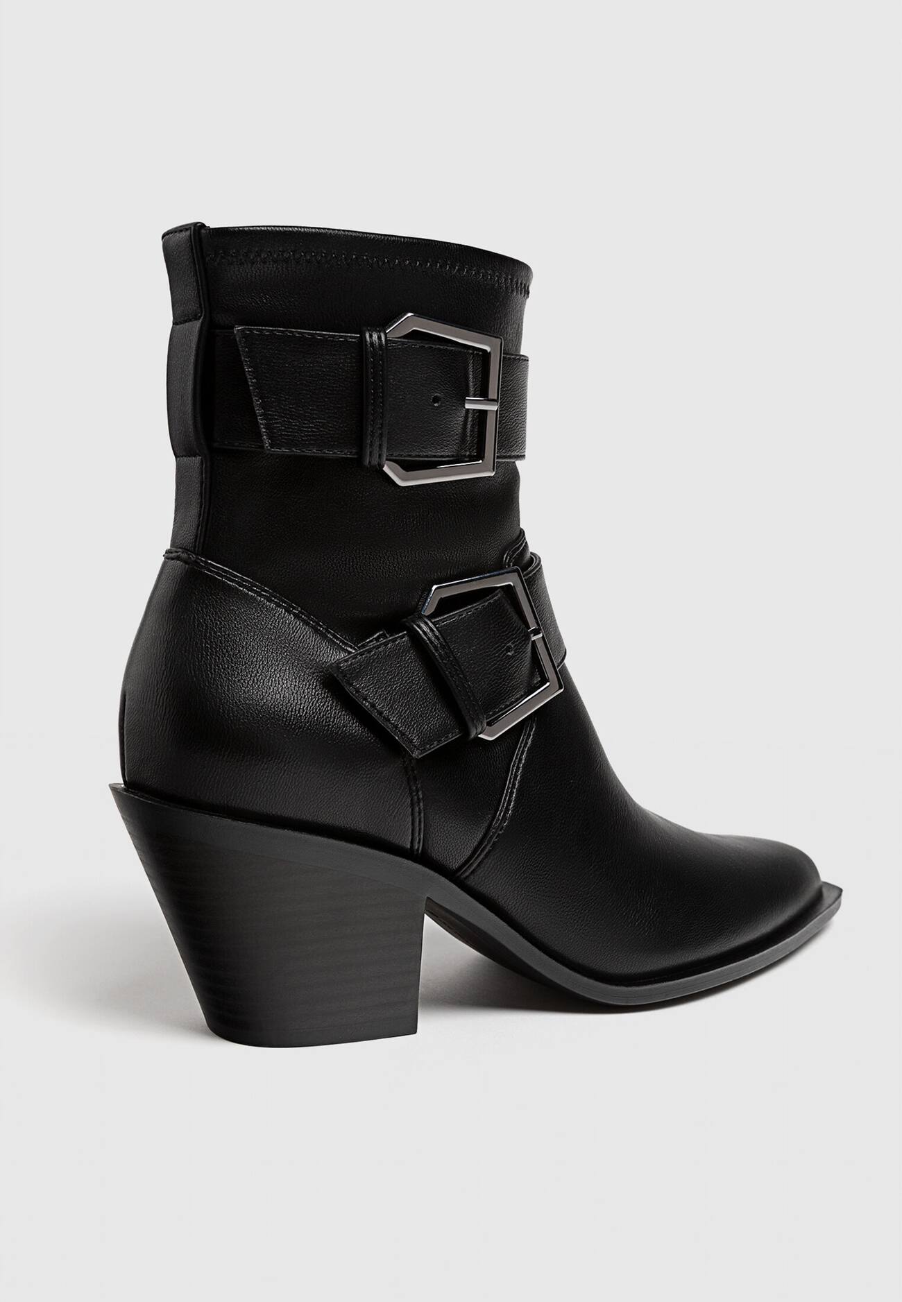 Botas pretas de cano curto com salto alto e fivelas.