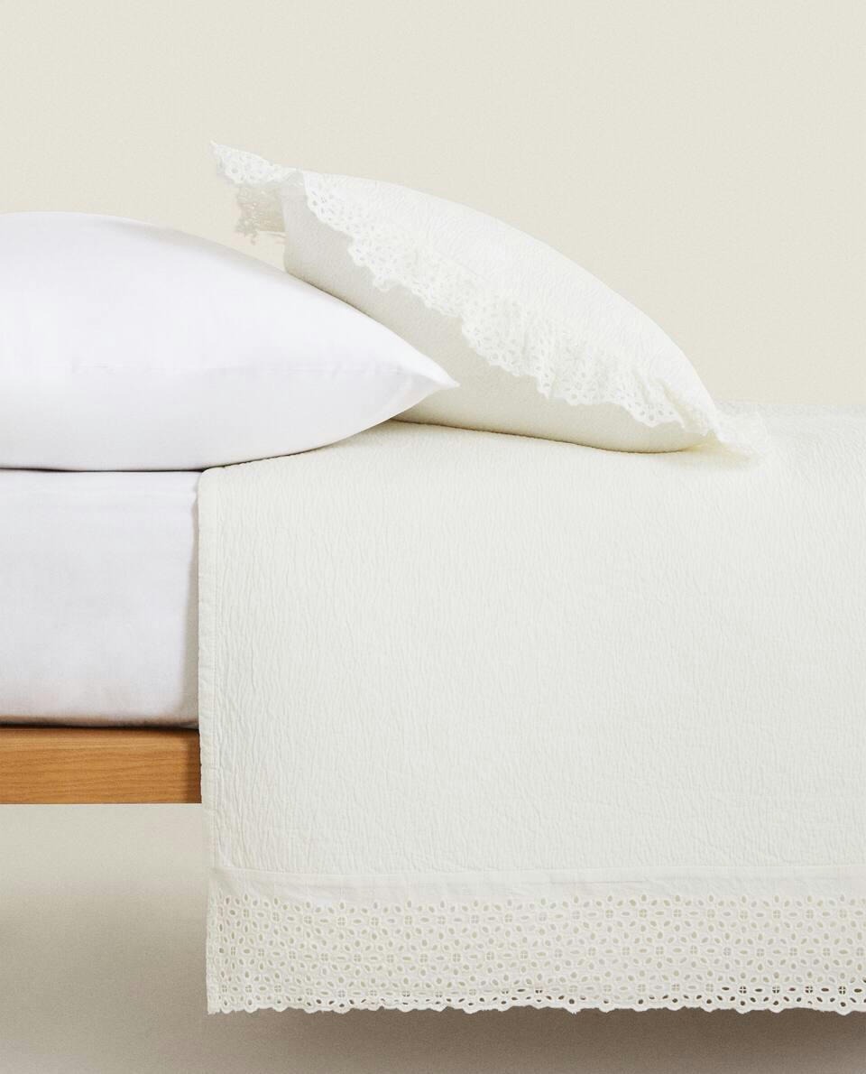 Colcha de algodão com detalhes bordados e franzidos.