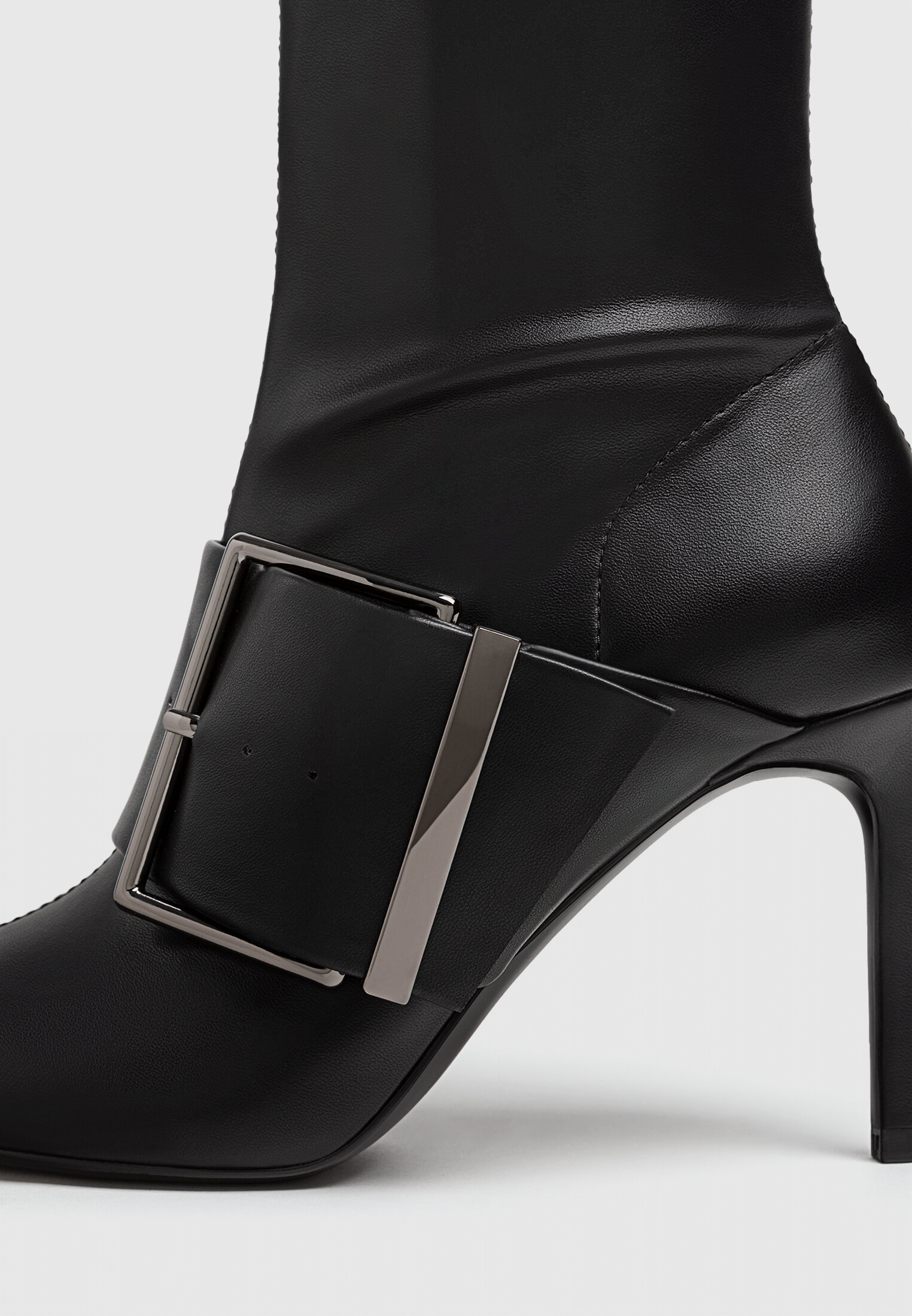 Botas pretas de cano curto com salto alto e fivelas.
