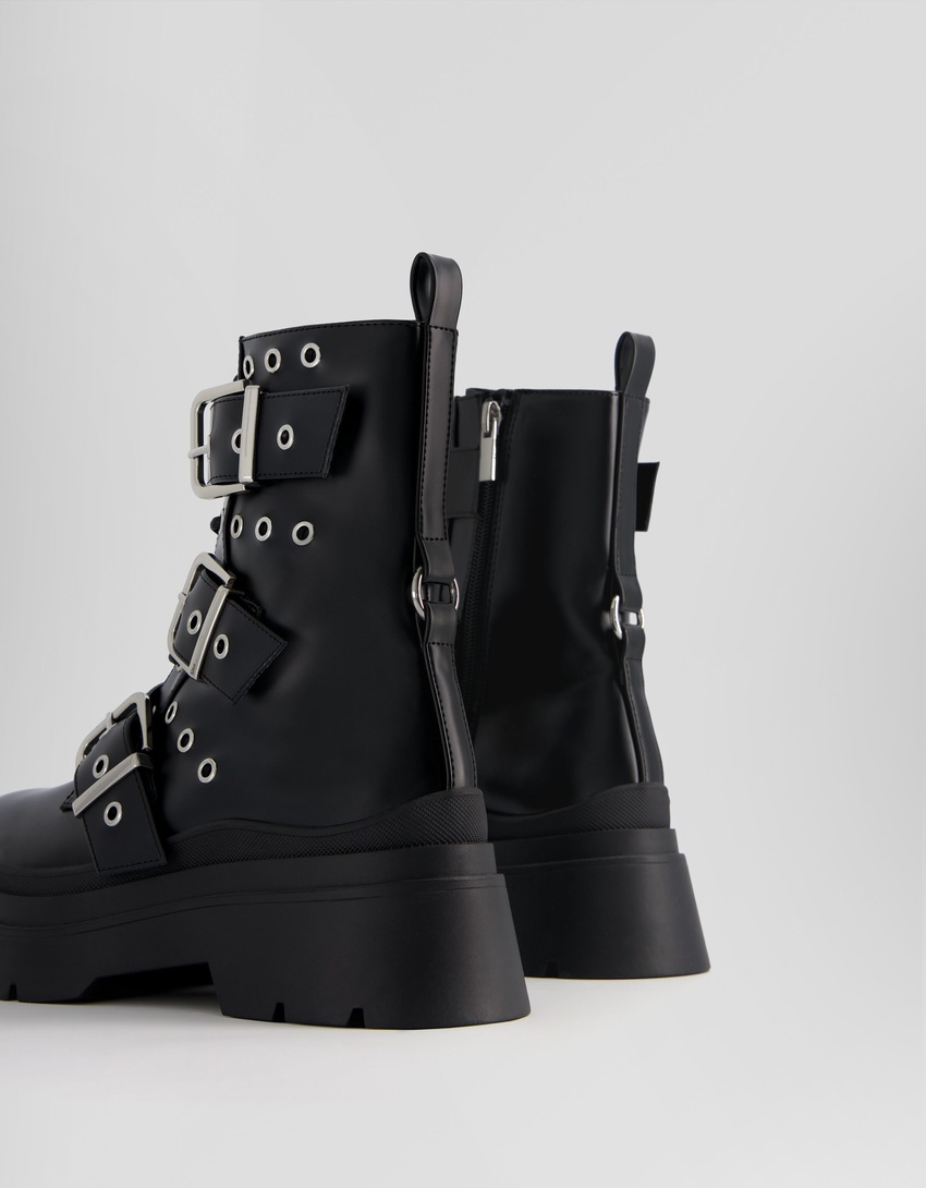 Botas de cano curto sem salto, com tiras, ilhós e fivelas.