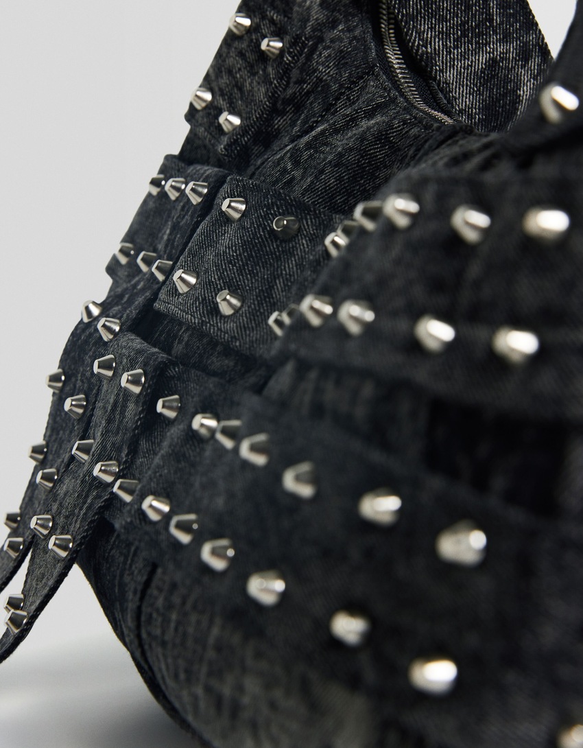 Bolsa de ombro ajustável em jeans com alças cravejadas.