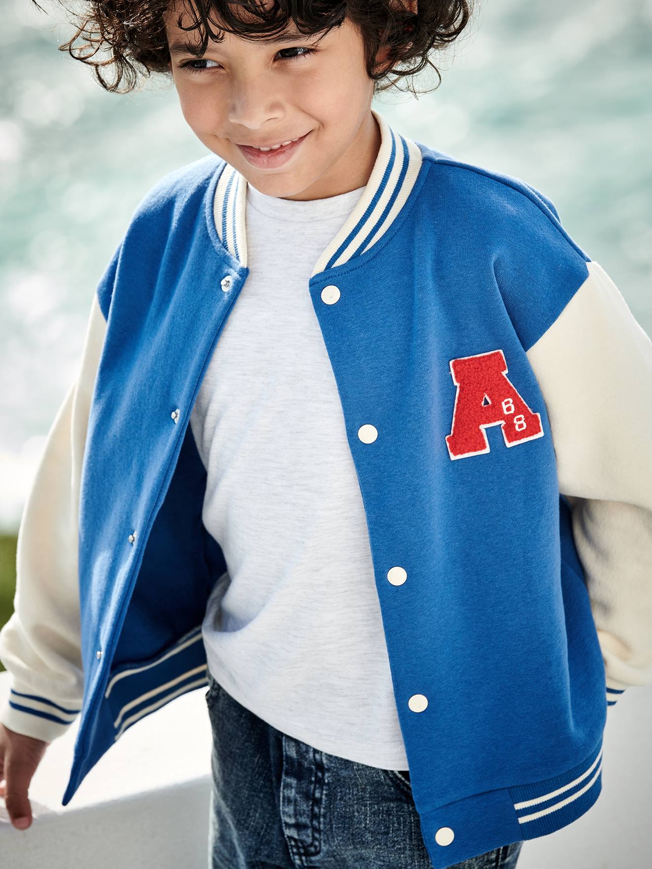 Moletom universitário azul infantil estilo teddy com botões de pressão na frente.