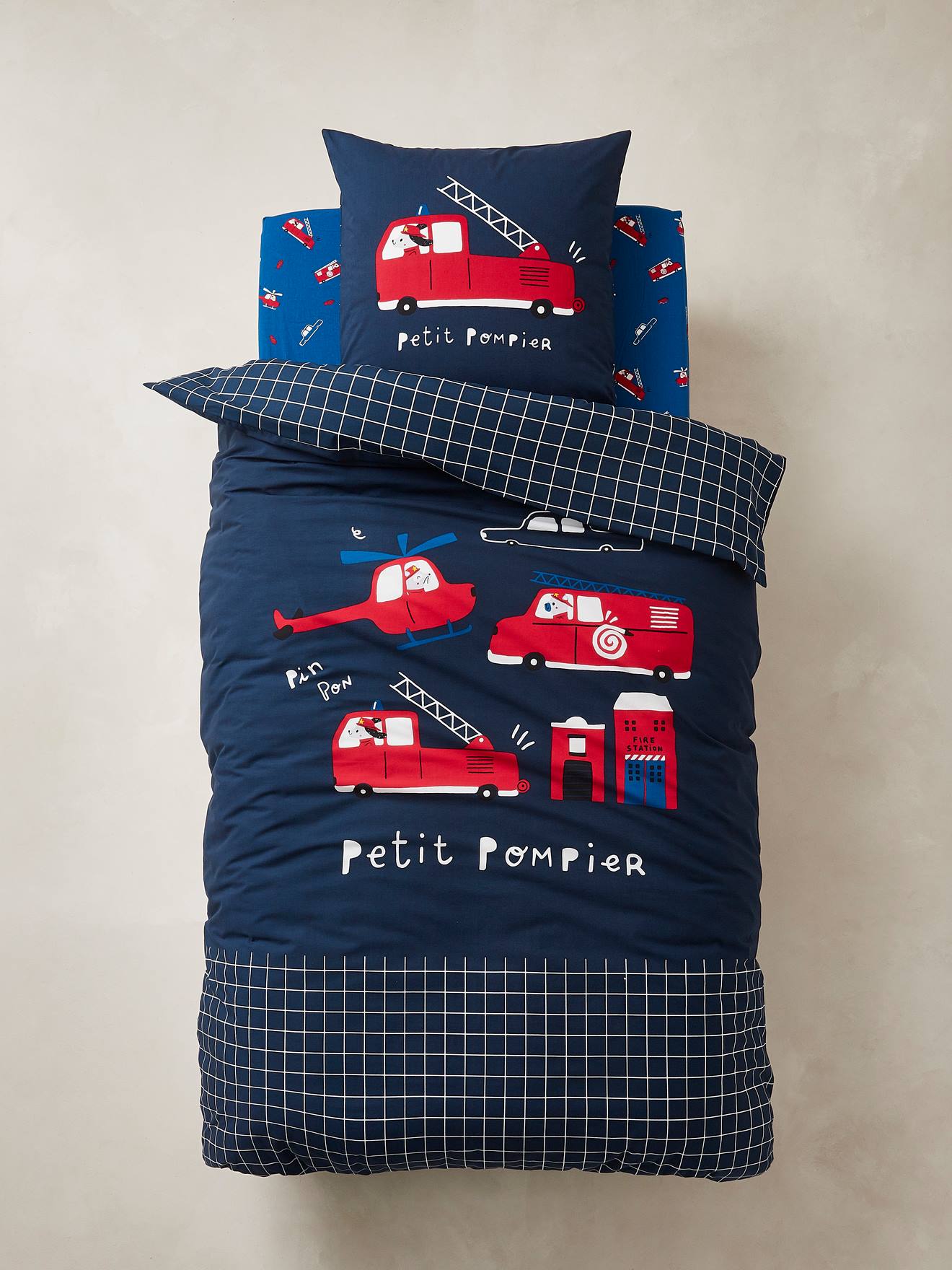 Conjunto infantil Petit Pompier com capa de edredom e fronha em azul escuro liso com motivos.