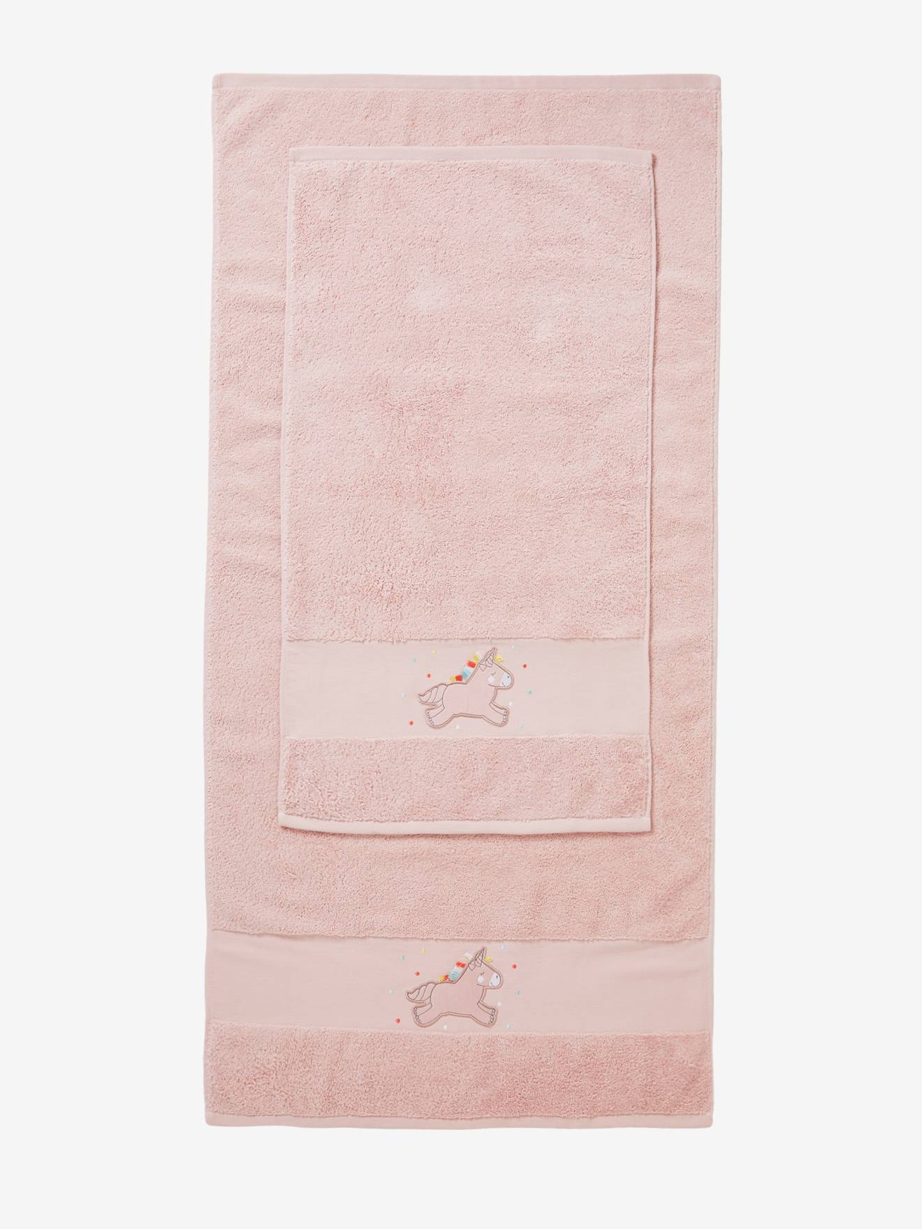 Toalha de banho lisa rosa claro com estampas de unicórnios.