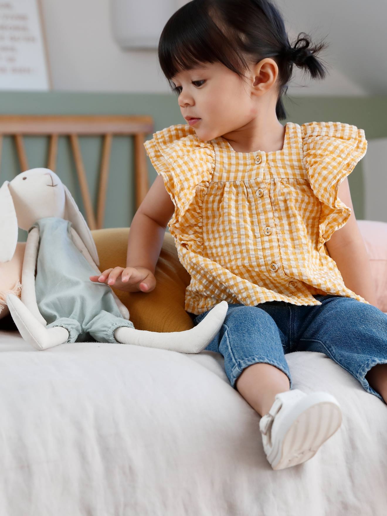 Conjunto infantil tamanho médio com blusa xadrez amarela e calça jeans de pernas largas.