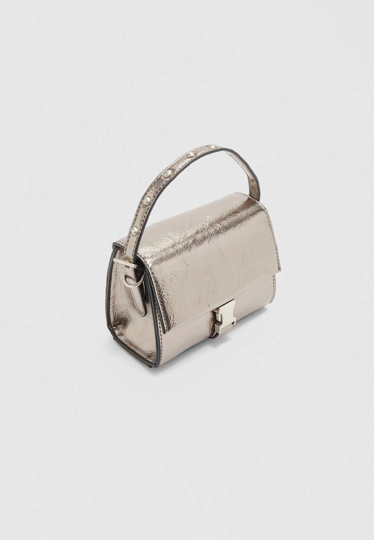 Bolsa transversal com tachas e aba.