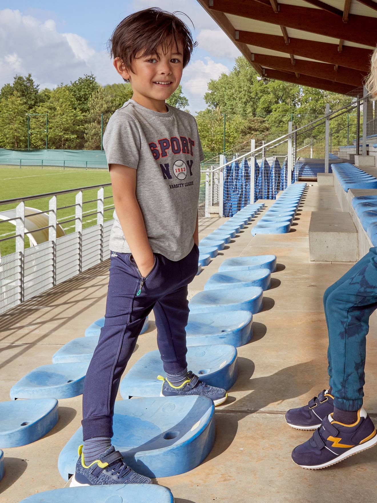 Calças esportivas infantis, em tecido técnico azul-escuro liso com estampas.