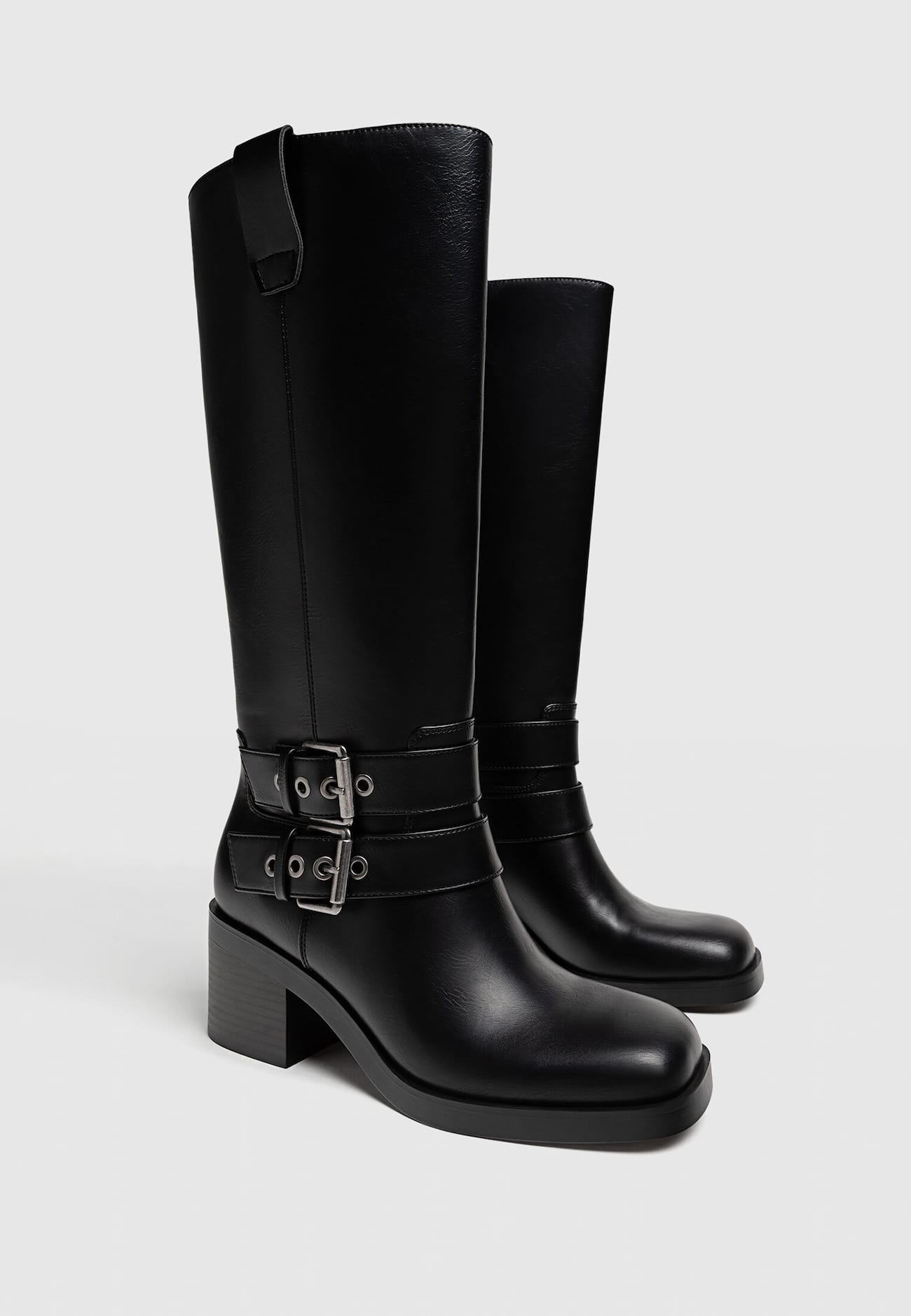 Botas pretas de motociclista com salto e fivelas.