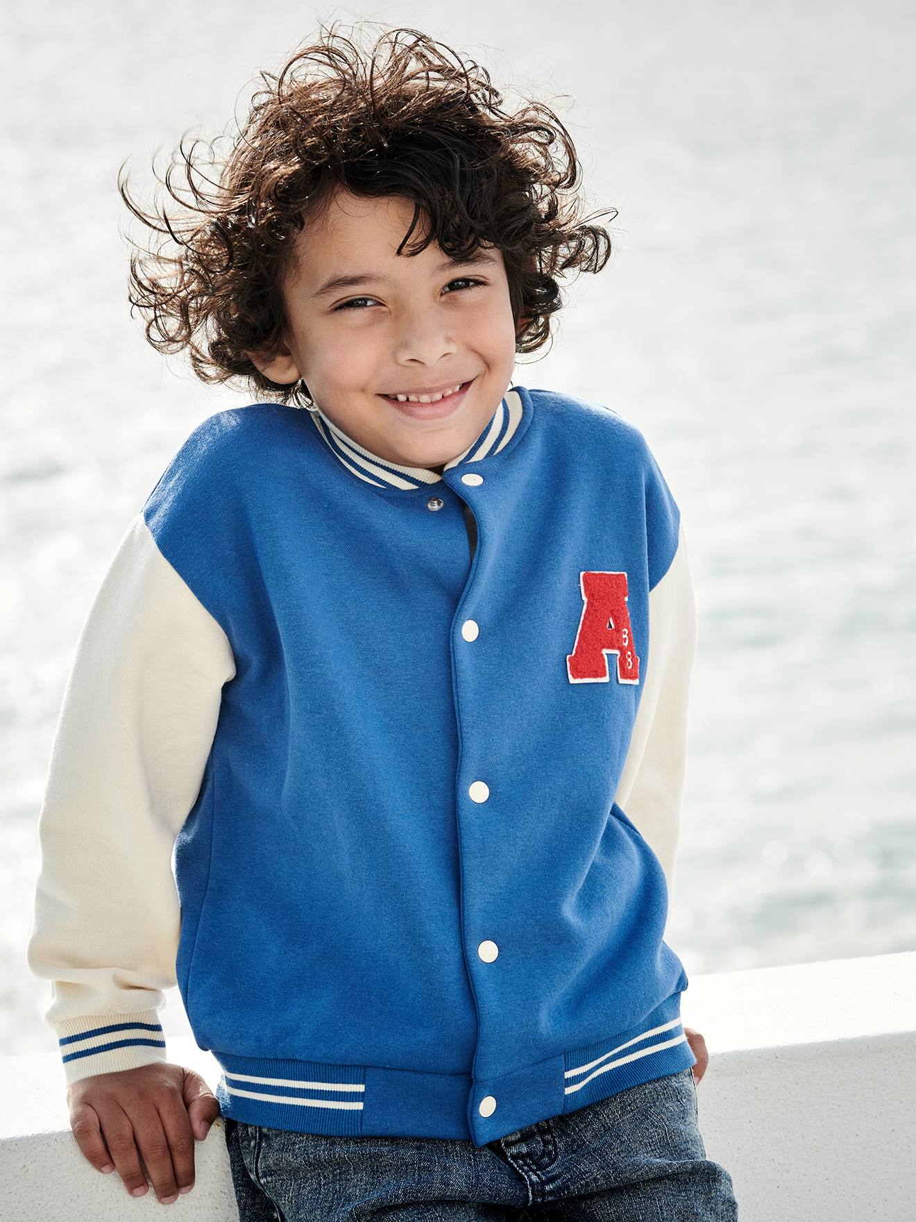 Moletom universitário azul infantil estilo teddy com botões de pressão na frente.
