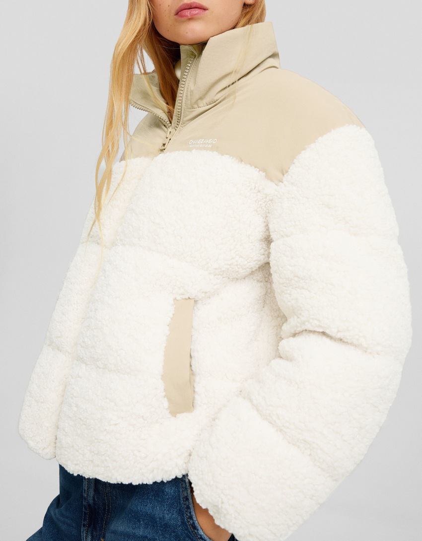 Jaqueta puffer com detalhes contrastantes em imitação de pele de carneiro e nylon.