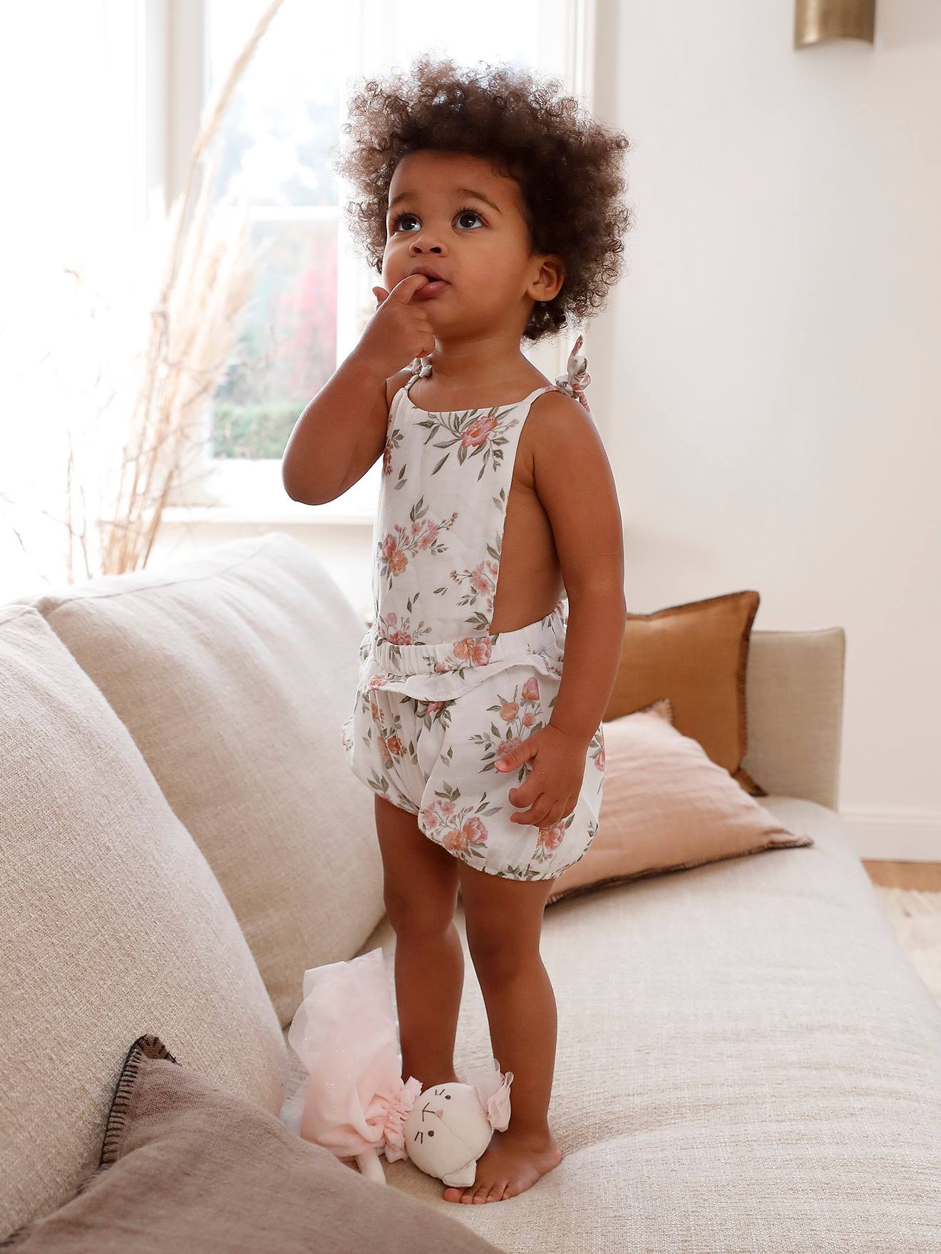 Macacão branco para bebê com estampa floral e suspensórios.