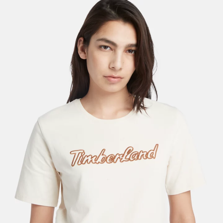 Camiseta feminina bege com logo texturizado.