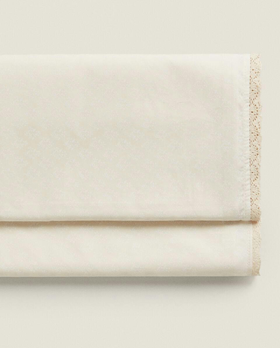 Lençol de cima infantil com estampa floral e acabamento em renda.