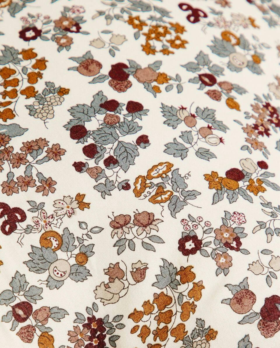 Almofada infantil em formato de estrela, em tecido com estampa floral.