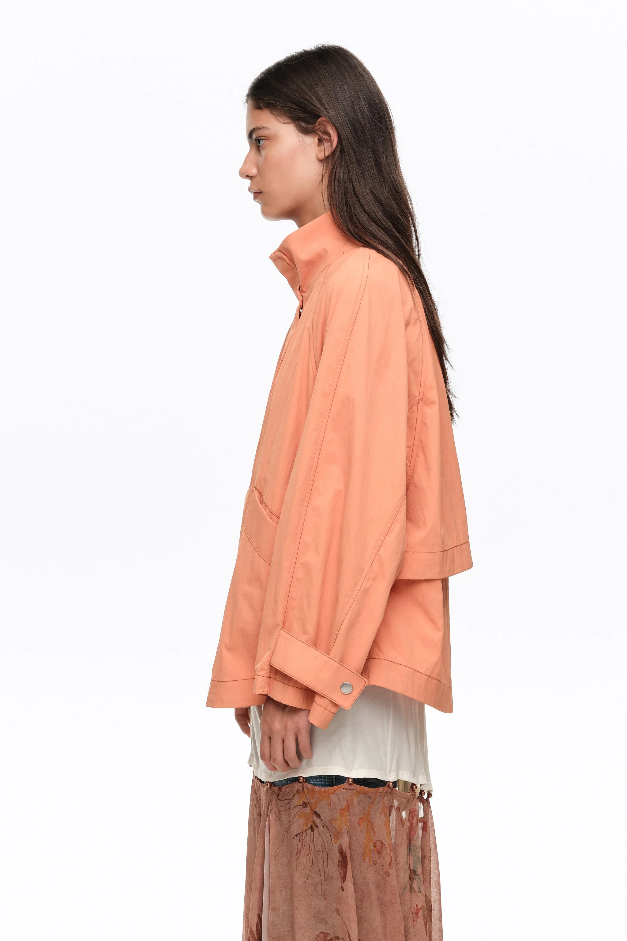 Trench coat curto, laranja, fluido, com gola alta.