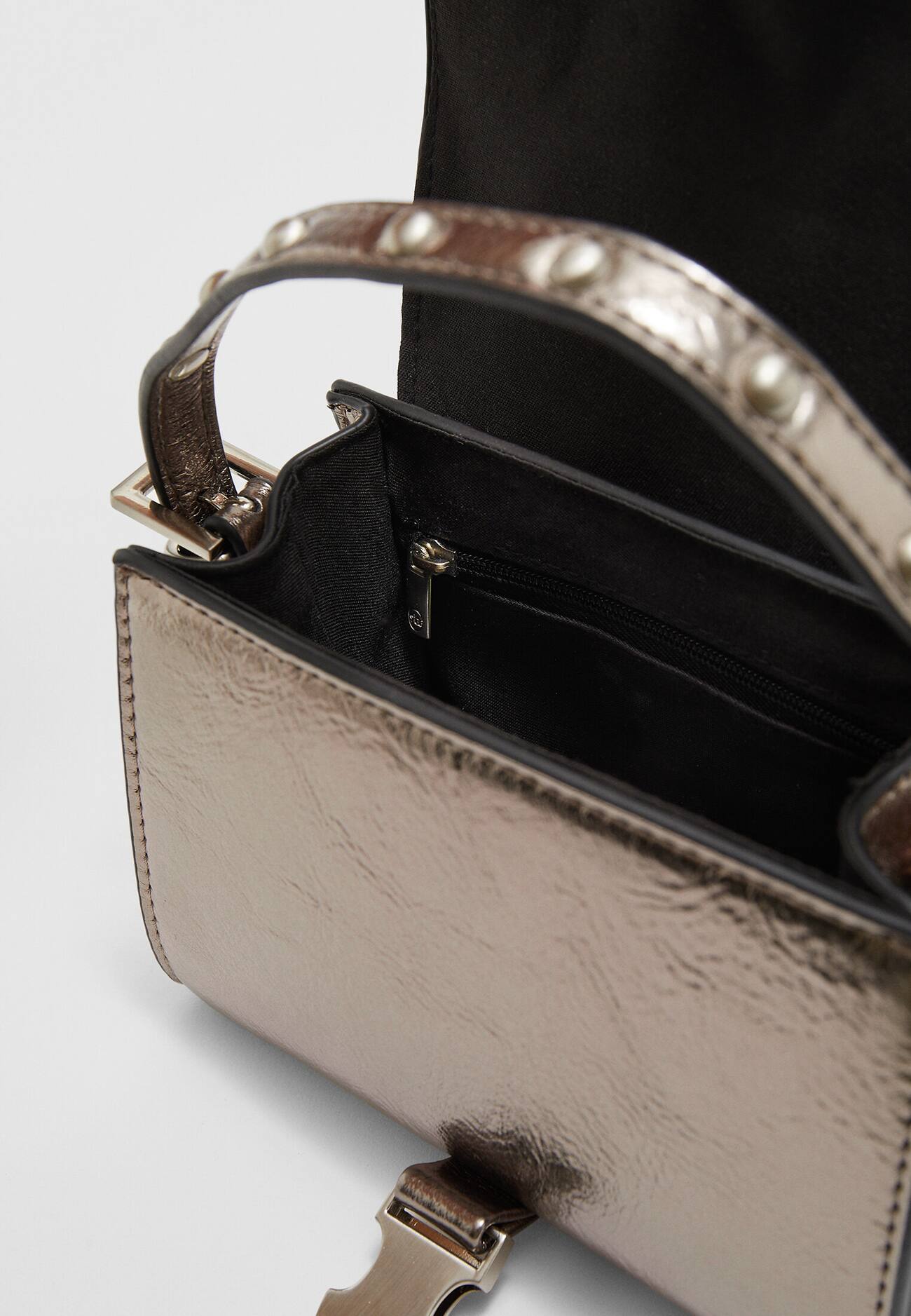 Bolsa transversal com tachas e aba.