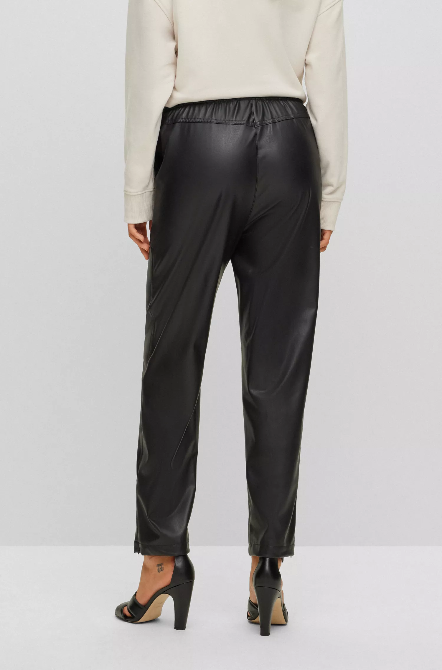 Calça BOSS laranja, corte relaxado, em tecido revestido, com cintura ajustável por cordão.