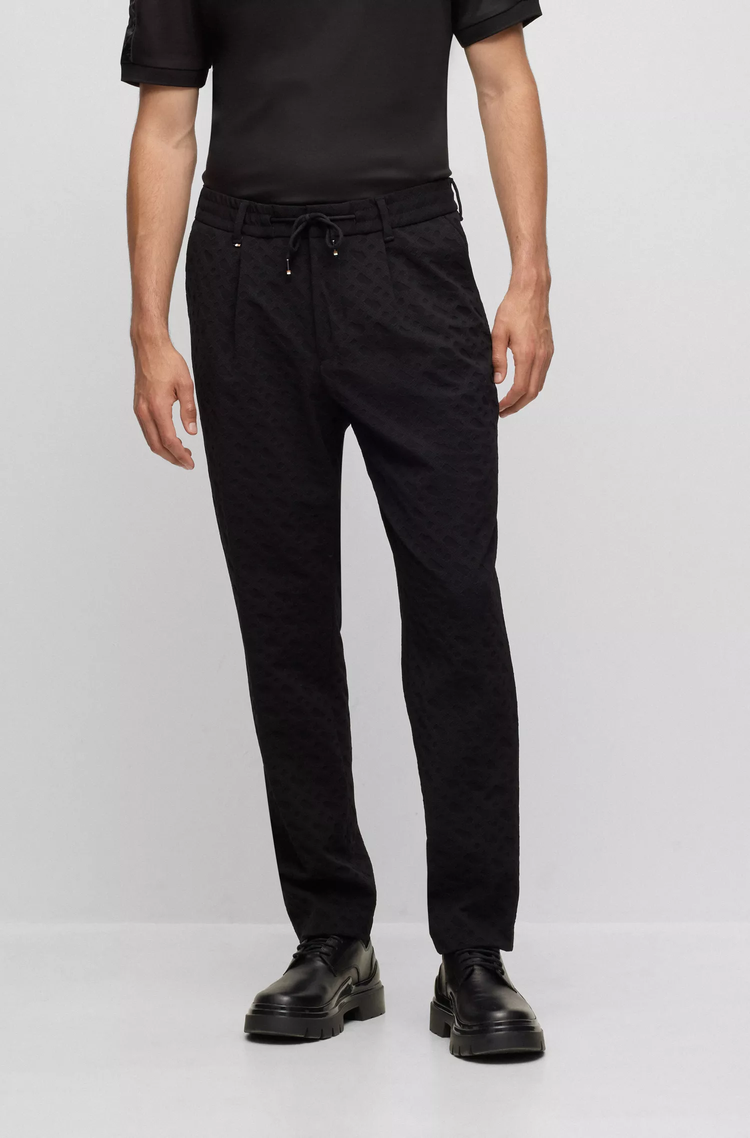 Calça BOSS preta de corte relaxado em tecido elástico com monograma.