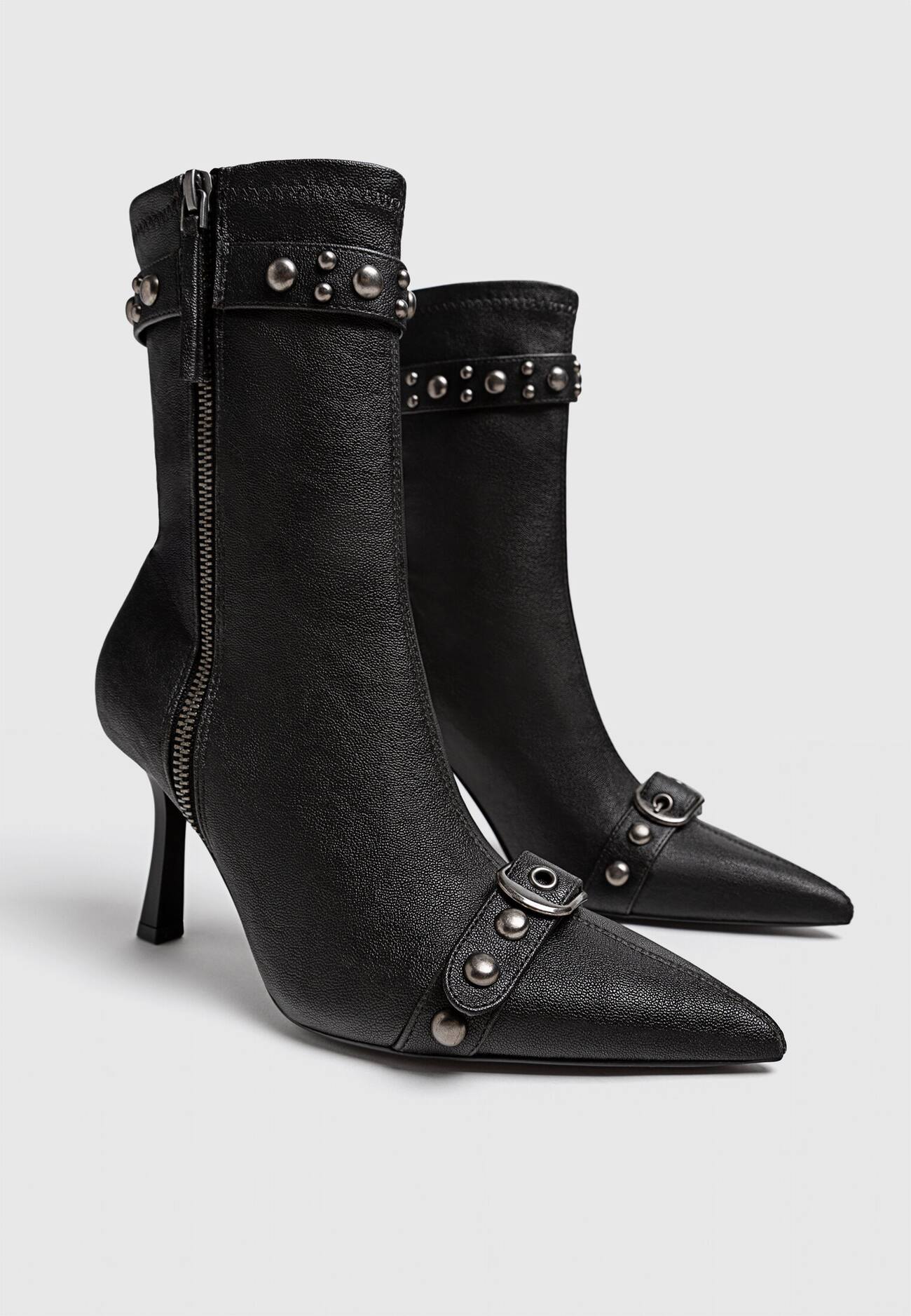 Botas de cano curto com tachas e fivelas em estilo desgastado.