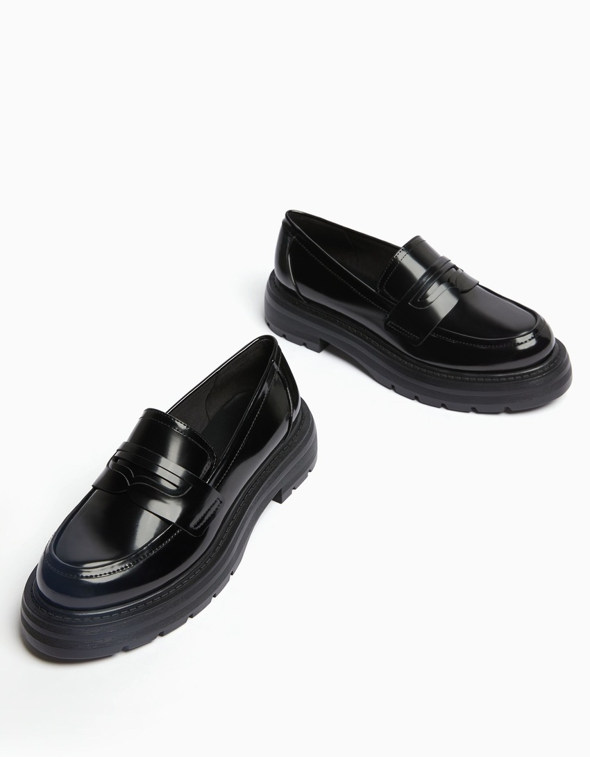Mocassins com tira de metal e solado tratorado.