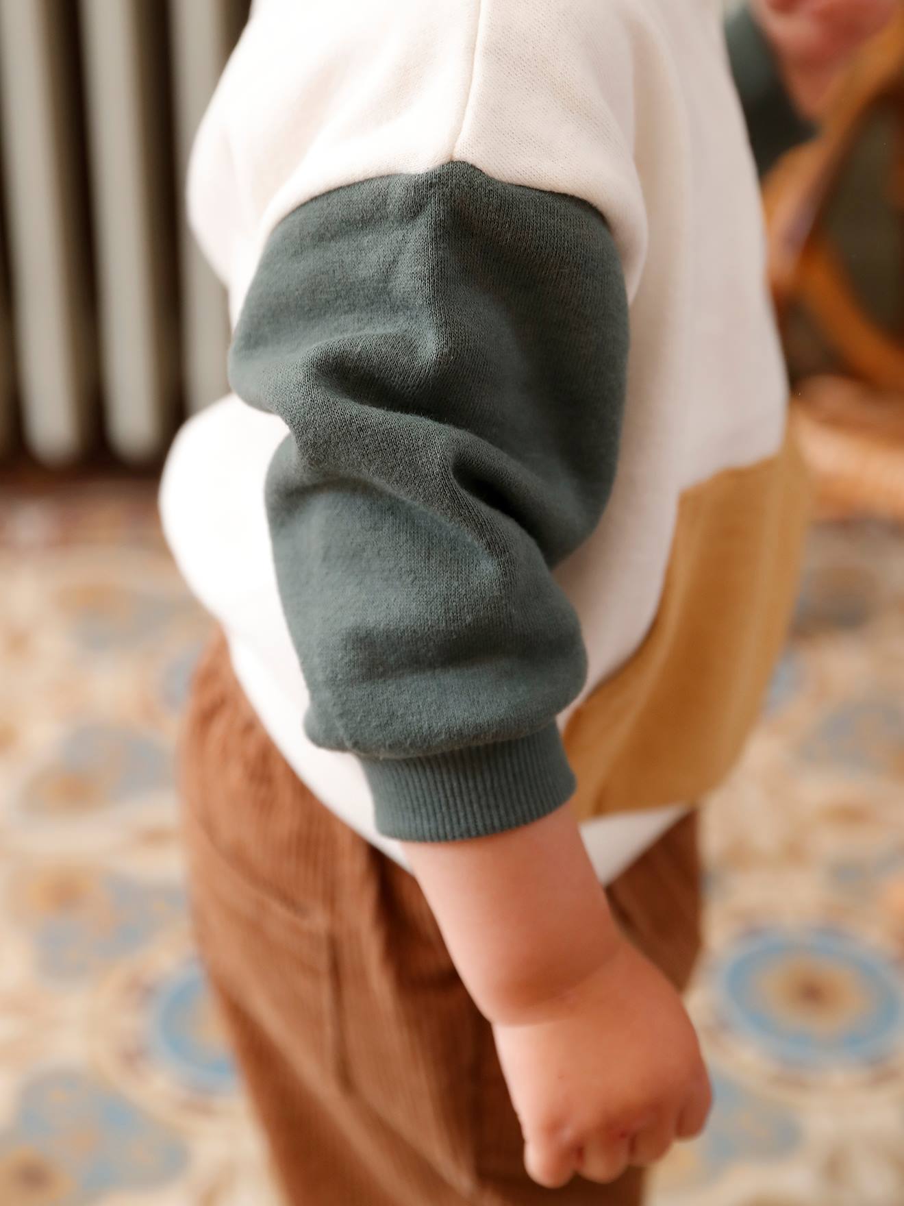 O conjunto para bebê inclui um moletom de lã e calças de veludo, em branco claro liso com estampas.