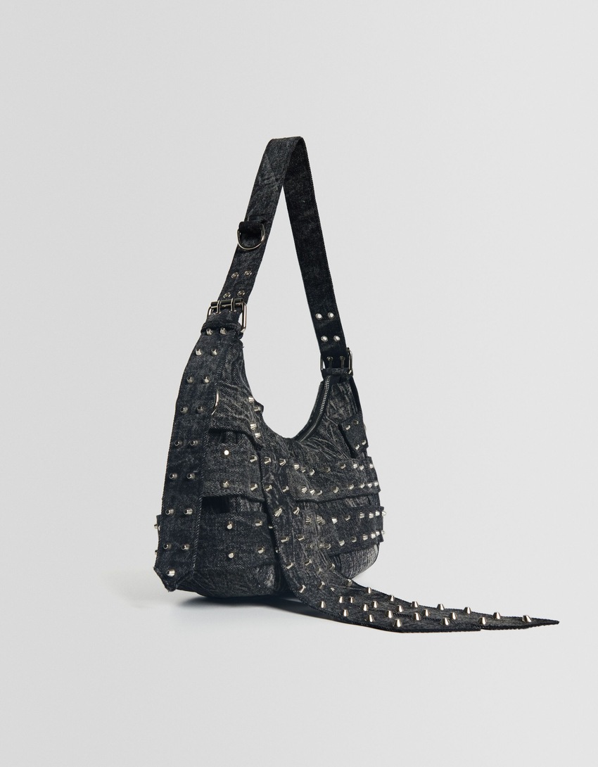 Bolsa de ombro ajustável em jeans com alças cravejadas.