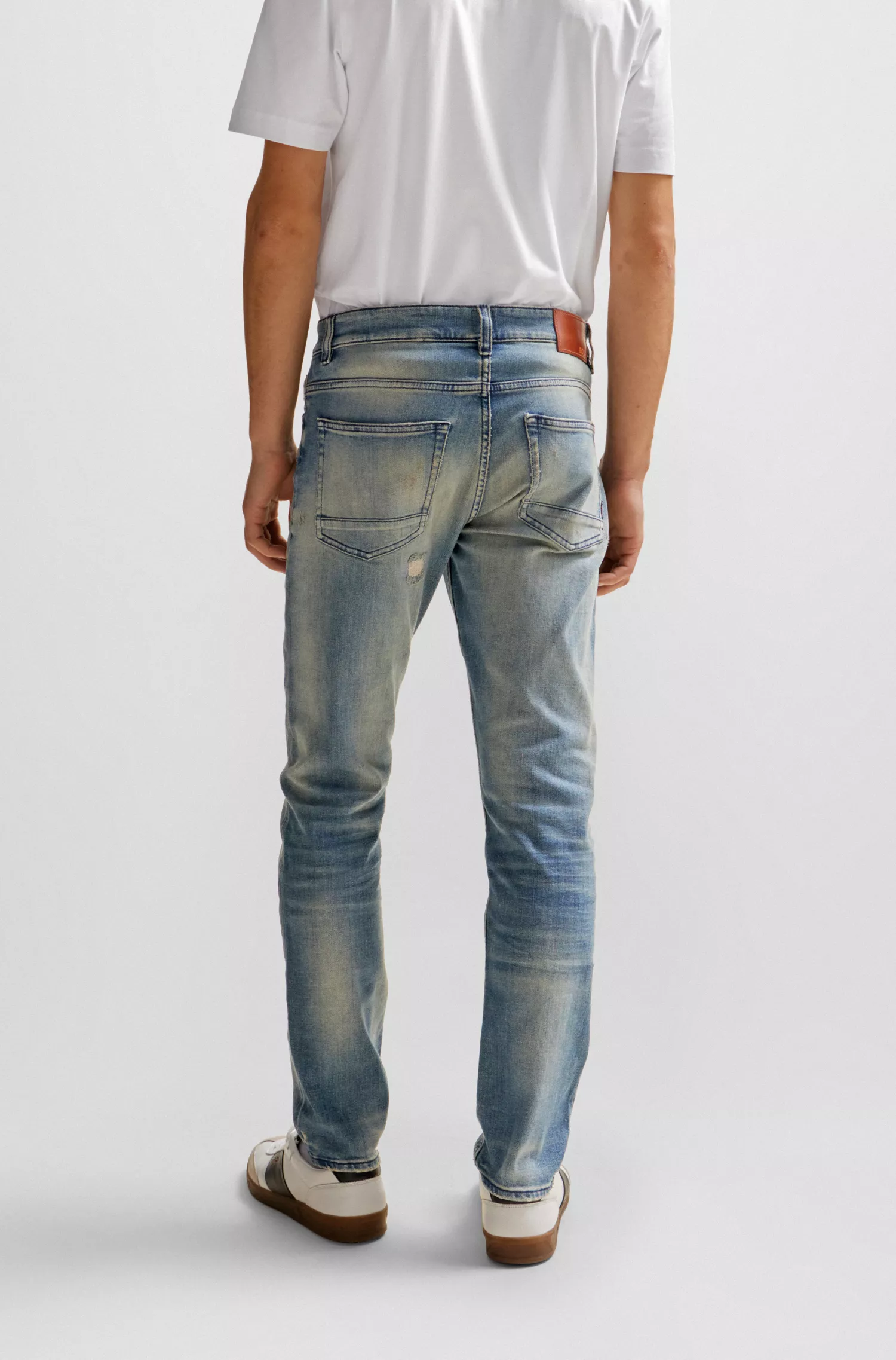 Calça jeans BOSS laranja, corte slim, em denim azul com tonalidade bege.