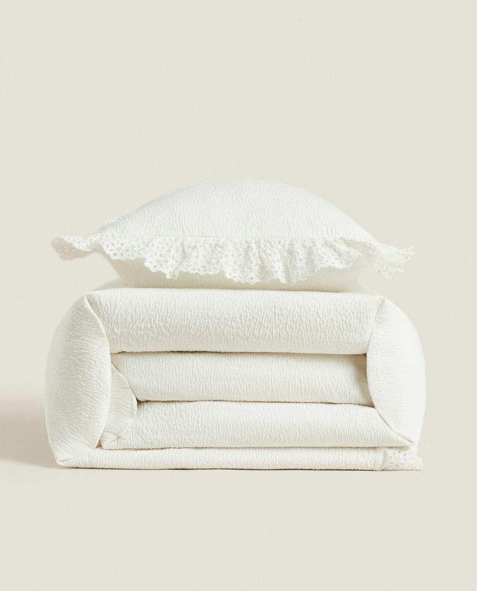 Colcha de algodão com detalhes bordados e franzidos.