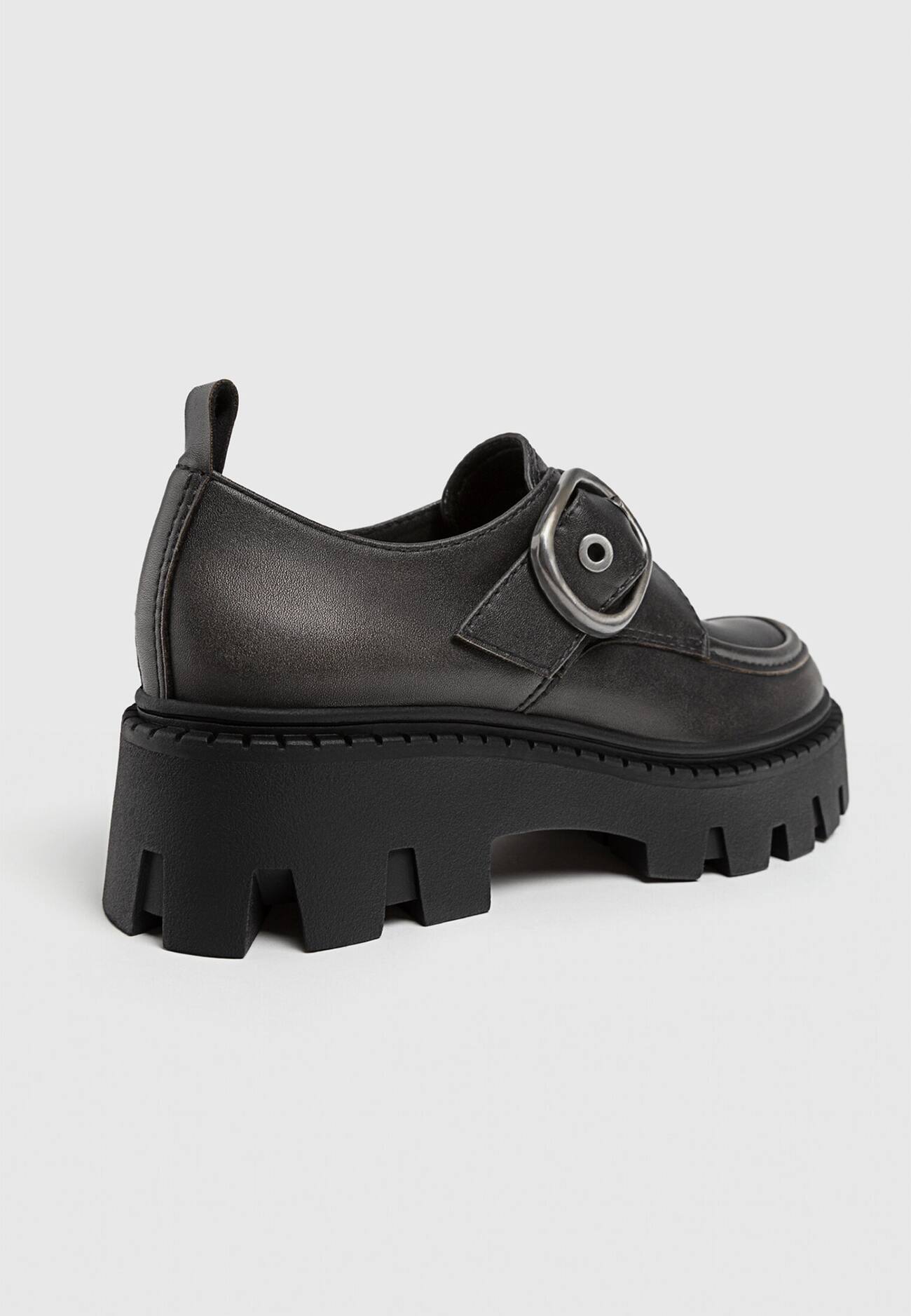 Sapatos baixos com fivela e solado tratorado.
