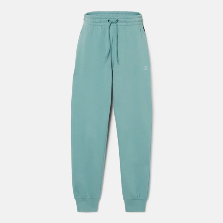 Calça de fato de treino feminina com bordado de árvore na cor verde-azulada.