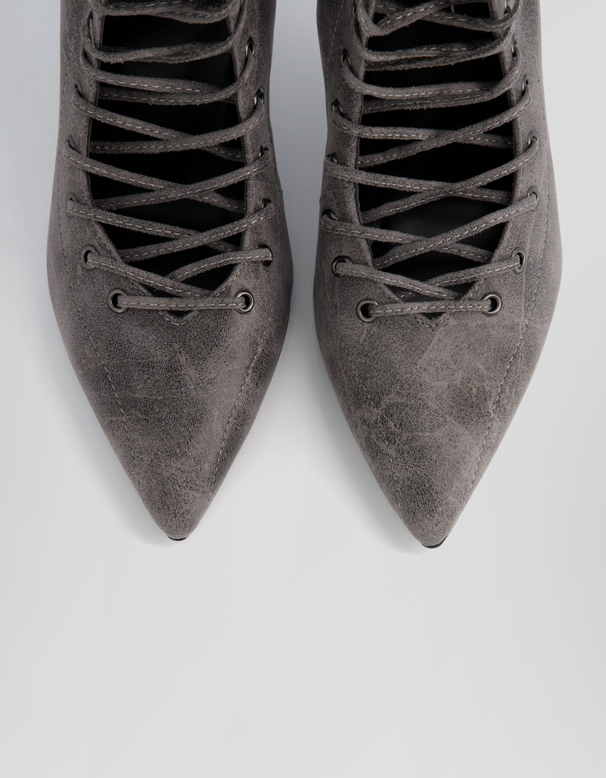 Botas de cano curto com cadarço, salto agulha e zíper.